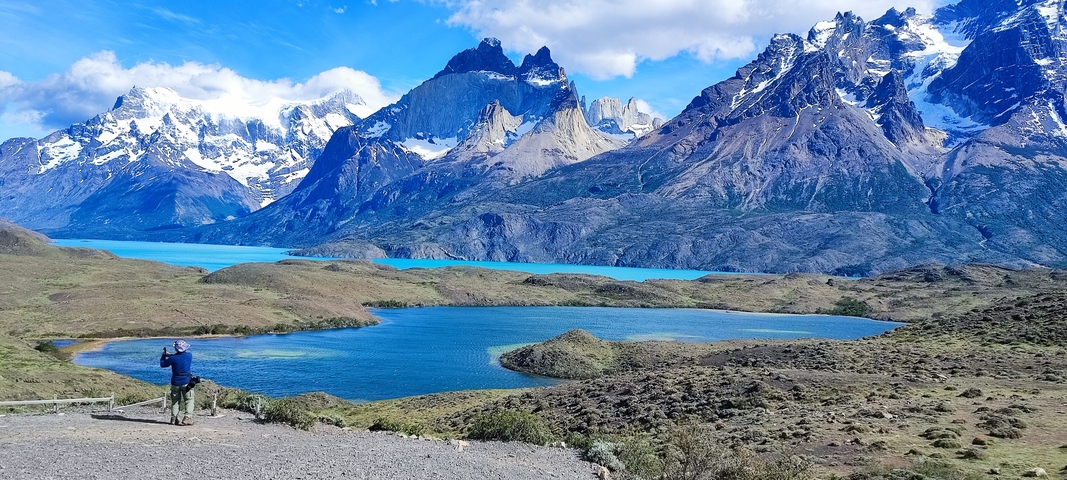       Beautiful mountain landscape with a lake and a person taking photos.
  