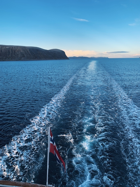       Blue ocean with a ship's wake extending into the distance.
  