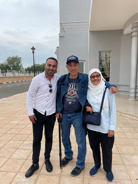 Group of three people posing together outdoors.