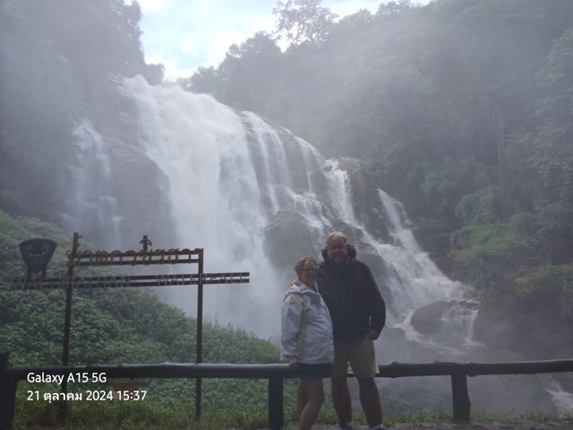       Two people posing in front of a large waterfall.
  