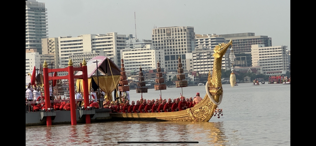       Ornate boat with people on a river in an urban area.
  