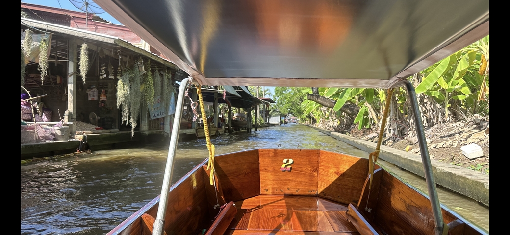       View from a boat on a narrow waterway lined with buildings.
  