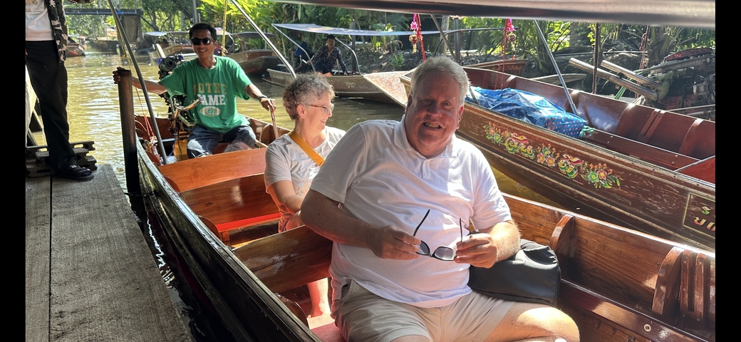       People sitting in a boat on a canal.
  
