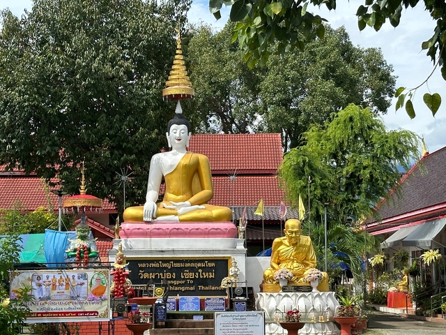 Large Buddha statue in an outdoor setting with smaller figures.