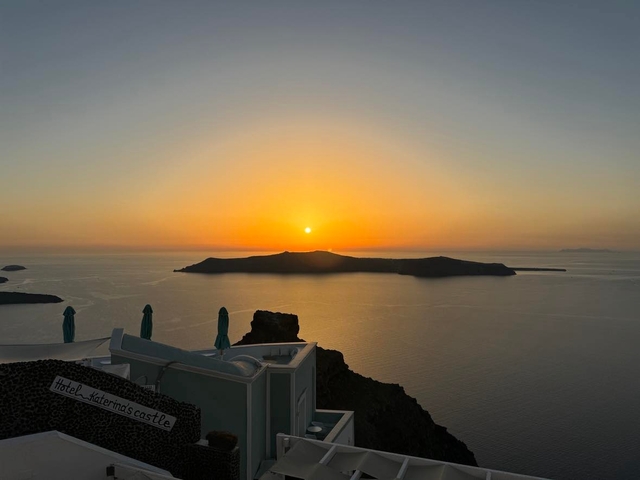       Sunset over an island in a serene sea.
  