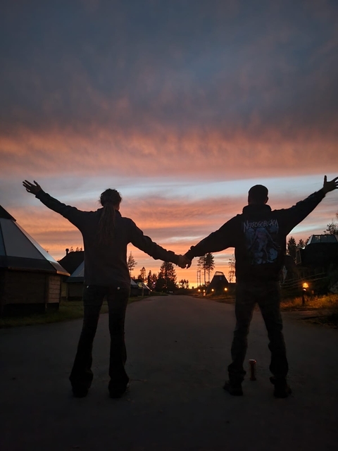 Two people holding hands against a vibrant sunset.