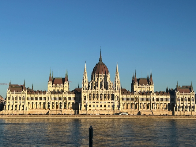       Panoramic view of a grand building by the river.
  
