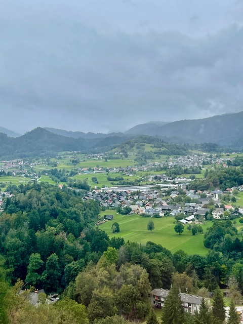 Wide valley with small houses and green hills in the background.