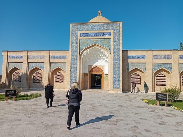       Visitors approaching a mosque with blue detailing.
  