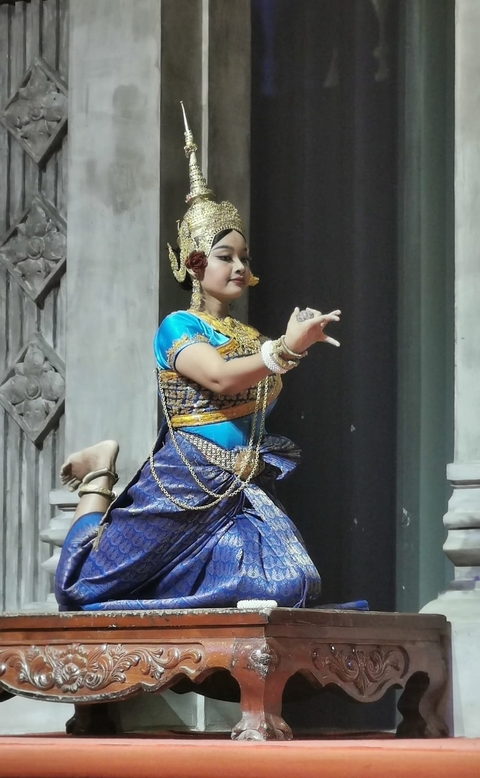 Traditional dancer in colorful attire performing on stage.