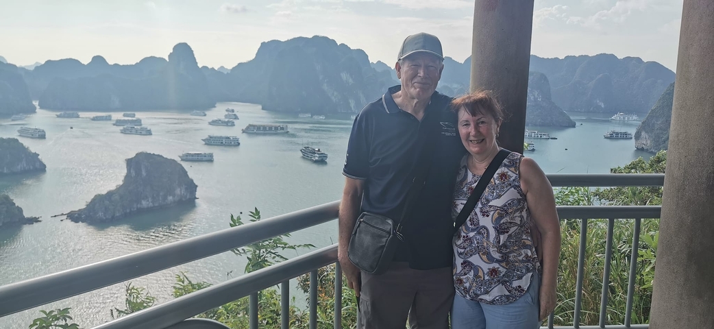 Two people posing on a balcony overlooking Halong Bay.