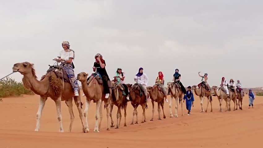 People riding camels in the desert.