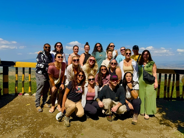       Large group of people posing with a view of a valley.
  