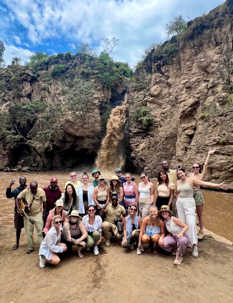       Large group posing by a muddy waterfall.
  