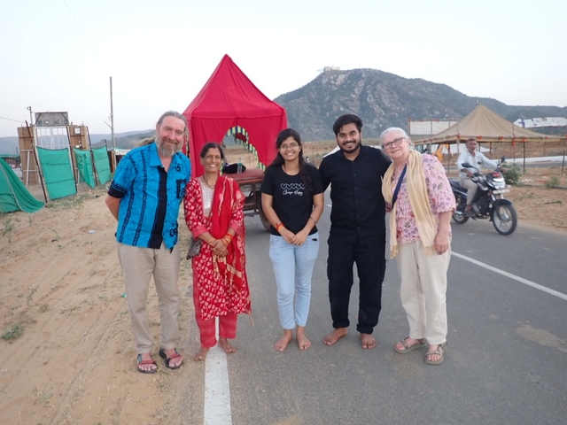 Group of people posing with a hilly landscape in the background.