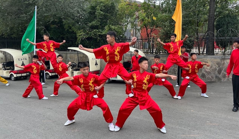 Martial artists performing in matching red uniforms outdoors.
