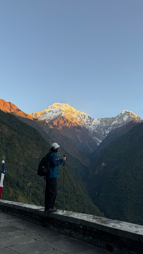Person looking at snow-capped mountains during sunrise.