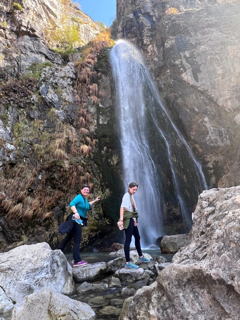 Two people standing in front of a waterfall.