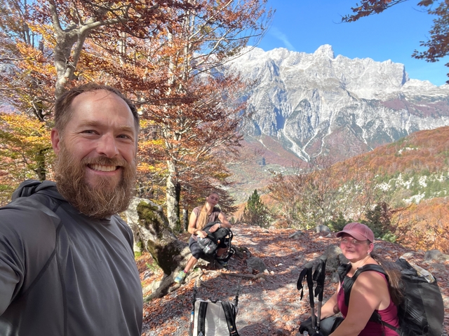 Three people posing in a mountainous forest area.