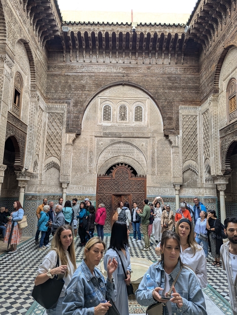       A group of tourists in front of intricate architecture.
  