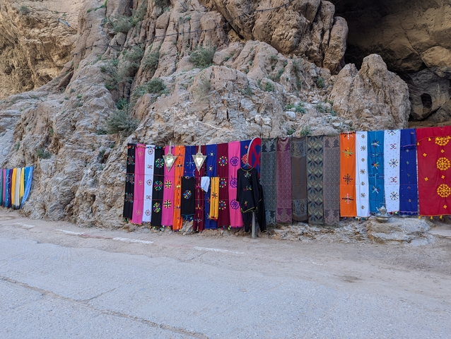       Colorful textiles displayed on a rock wall.
  