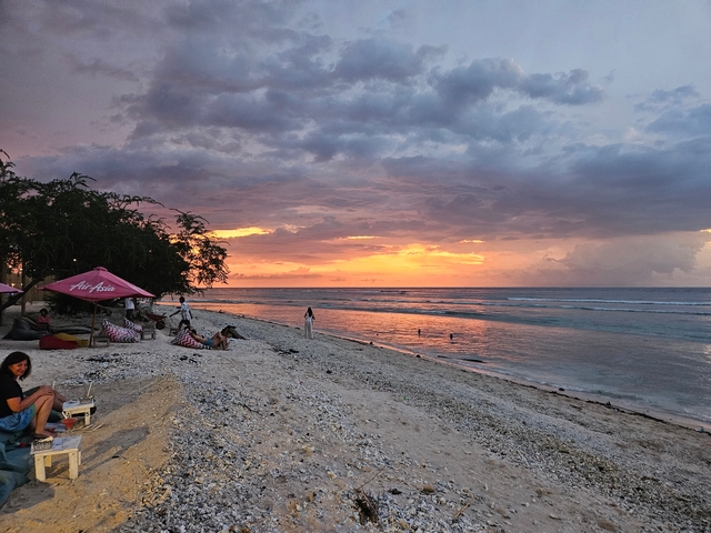       People relaxing on a beach at sunset.
  