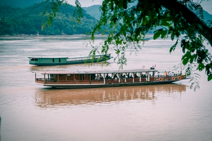       Long wooden boat sailing on a brown river.
  