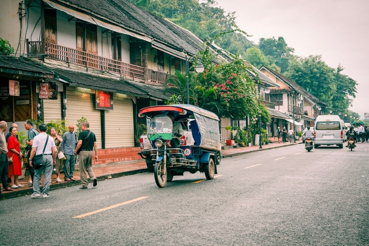       City street with a tuk-tuk and pedestrians.
  
