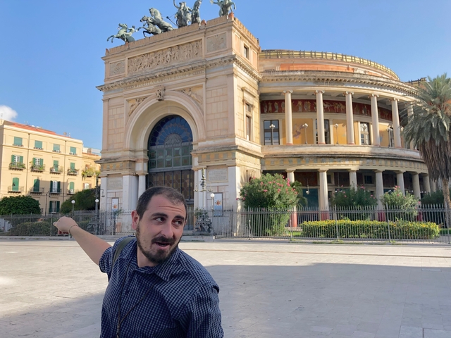       Man pointing to historical building with dome.
  