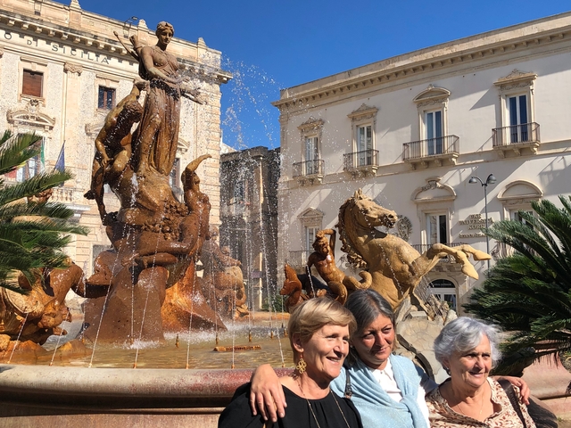       Four elderly women posing in front of a fountain.
  