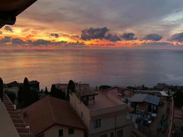       Sunset view over the sea with foreground rooftops.
  