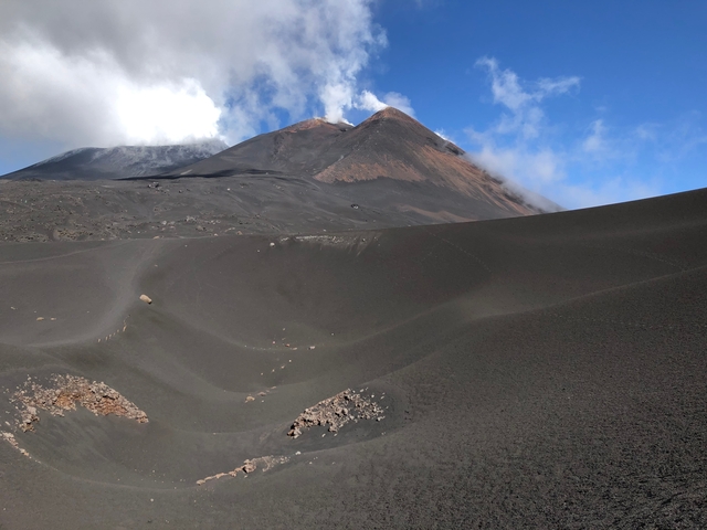      Black volcanic landscape with smoking peak.
  