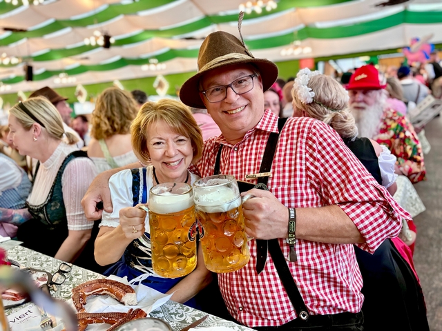 A couple toasting with large beer mugs at Oktoberfest.