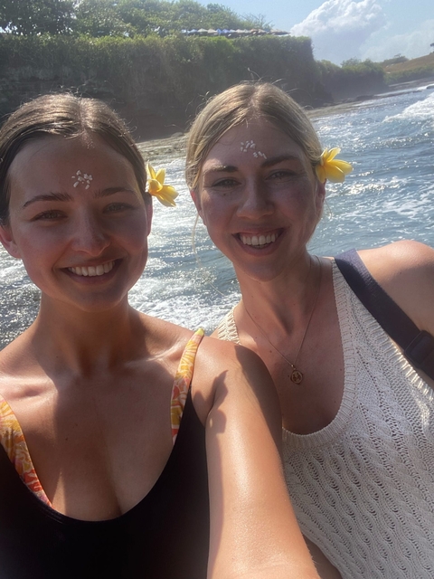       Two women smiling by the seaside.
  