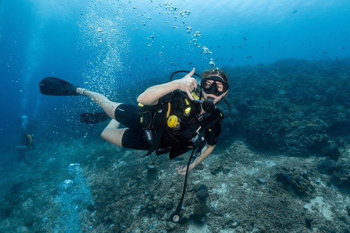       Underwater scuba diver raising a thumb up.
  