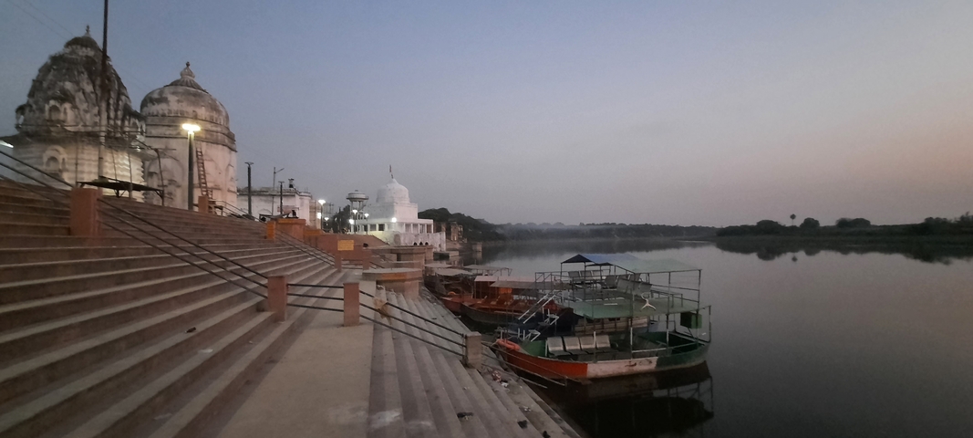       Riverside scenery with docked boats and temples.
  