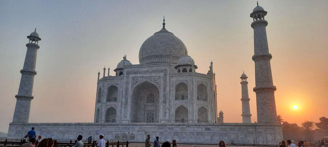 The majestic Taj Mahal with a crowd of people at sunset.
