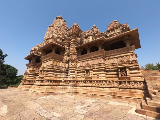       Ancient stone temple in an open area with clear blue sky.
  