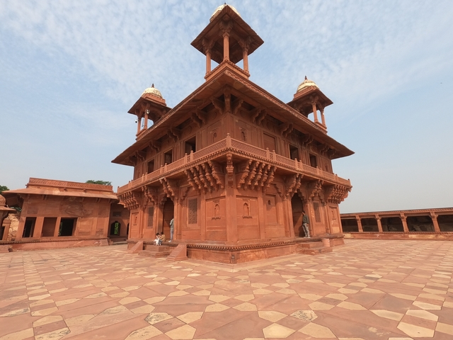       A large historic building with intricate architecture in red sandstone.
  