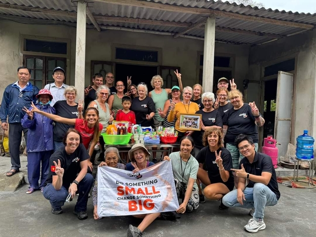Group photo in front of a house with a banner