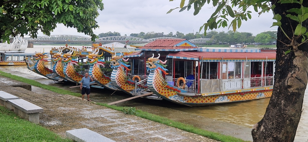 Colorful dragon boats docked along a river.