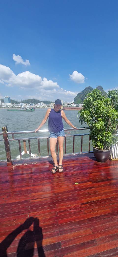 Woman posing on a boat with a cityscape in the background