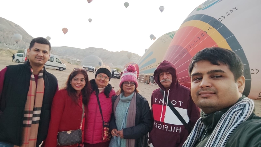      Group of people standing with hot air balloons on the ground.
  