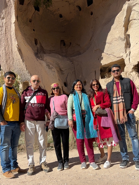 Group of people posing for a photo against a rocky background.