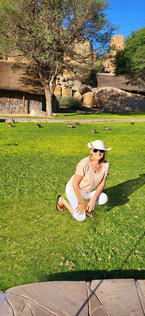 Woman posing on grass with small animals nearby.