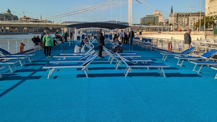       Open deck of a ship with lounge chairs and people.
  