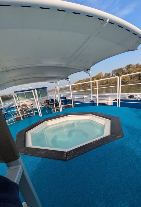       Deck of a river cruise ship with a hot tub and river view.
  