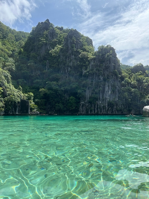 Turquoise water in a lagoon surrounded by tall cliffs.