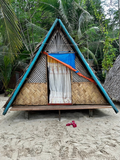 Traditional bamboo and thatch hut with a colorful curtain.