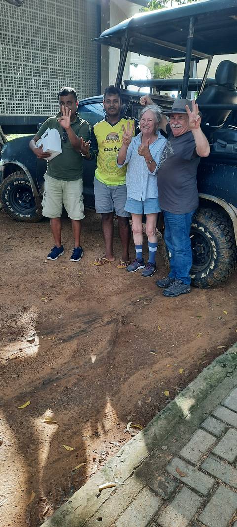       Close-up of people's feet standing on dusty ground.
  